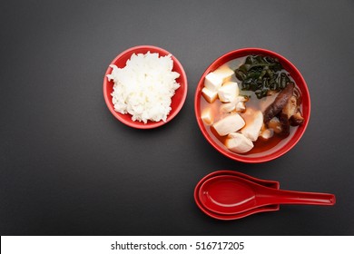 Japanese Miso Soup And Rice On A Red Bowl And Spoon On The Table.