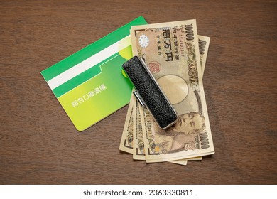 Japanese money and bankbook on wooden table. (Japanese written 'Bankbook')