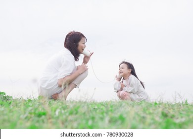 Japanese Mother And Daughter Playing With Paper Cup Phone