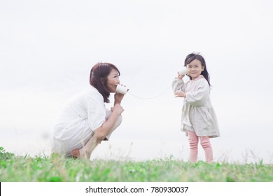 Japanese Mother And Daughter Playing With Paper Cup Phone