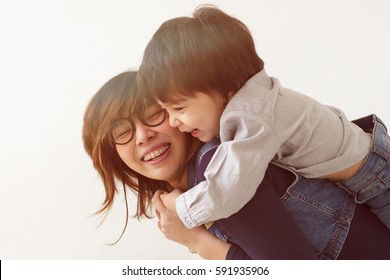 Japanese mother hugs her son, they laugh and smile. Warm family relations.