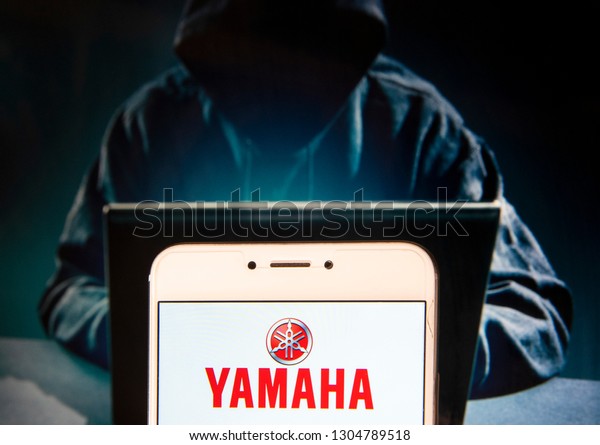 Japanese multinational automobile corporation\
Yamaha logo is seen on an Android mobile device with a figure of\
hacker in the\
background.