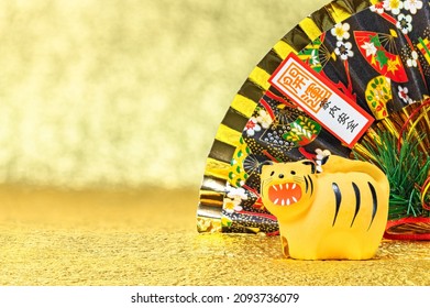 Japanese New Year's Greeting Card Depicting A Folding Fan Written Good Luck For A Safe House With A Zodiac Animal Figurine Of A Funny Roaring Tiger For The Year 2022 Against A Gold Background.