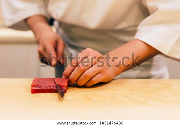 Japanese Omakase Chef cut bluefin tuna (Otoro in\
Japanese) neatly by knife on wooden kitchen counter for making\
sushi. Japanese luxury\
meal.