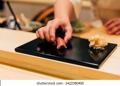 Japanese Omakase meal: Chutoro Sushi (Medium Fatty Bluefin Tuna) served by hand with pickled ginger on glossy black plate. Japanese traditional and luxury meal.