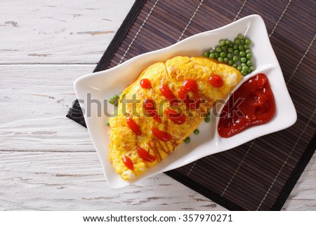 Japanese Omurice omelet stuffed with rice and chicken on a plate. horizontal top view