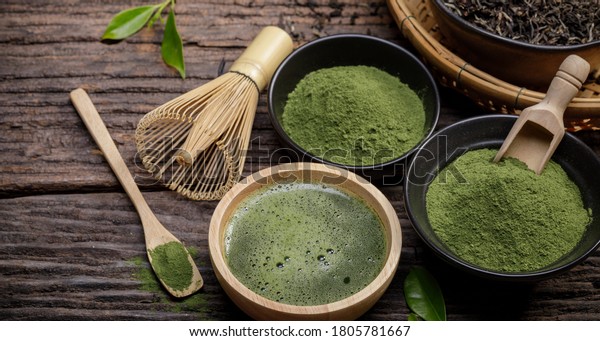 Japanese organic matcha\
green tea powder in bowl with wire whisk and green tea leaf on\
wooden background, Organic product from the nature for healthy with\
traditional style