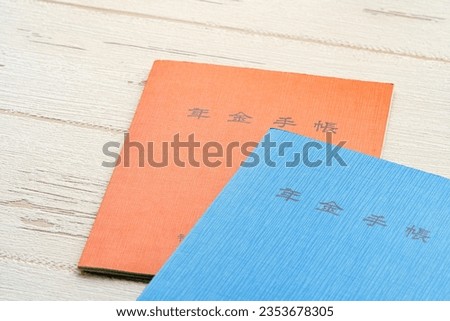 Japanese pension insurance booklet on wooden table. (Written 'pension book')