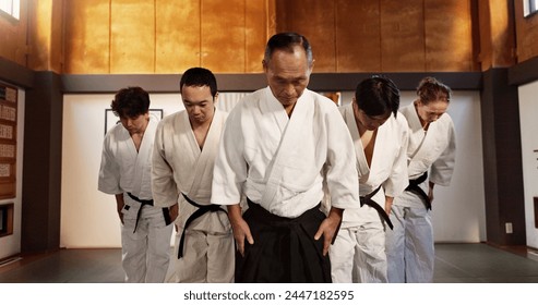 Japanese people, bow and respect in aikido in dojo place, training and modern martial arts class of self defence. Group, black belt students and sensei in honor and commitment in fighting discipline - Powered by Shutterstock