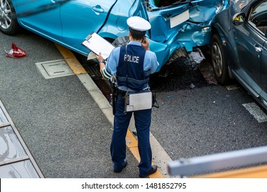 Japanese Police Officer Is Processing A Traffic Accident.