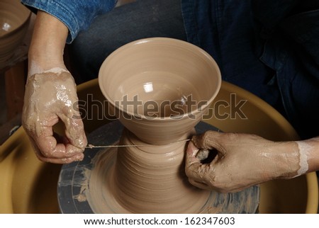 Japanese pottery master technique/Cutting the bowl/A Japanese pottery master cutting a finished bowl from the clay on his pottery wheel
