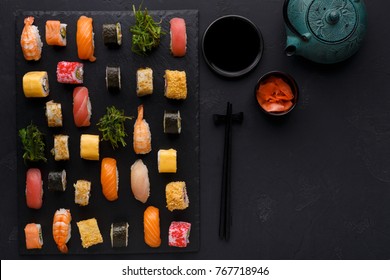 Japanese Restaurant, Sushi Roll Platter On Black Slate Plate. Set For One Person, With Chopsticks, Ginger, Soy, Top View