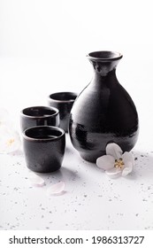 Japanese sake as traditional alcohol. Traditionally served sake in ceramics. Black ceramics on a white stone.