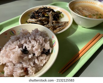 Japanese School Lunch On A Green Plastic Tray. Rice, Soup And Fried Anchovies 