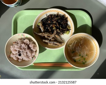 Japanese School Lunch On A Green Plastic Tray. Rice, Soup And Fried Anchovies 