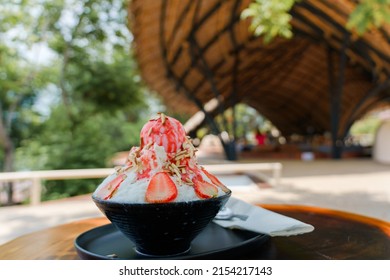 Japanese shaved ice dessert , Strawberry kakigori bingsu topped with sweet ice cream almond stick strawberry sauce and condensed milk in cafe. Traditional summer dessert menu in Japan.