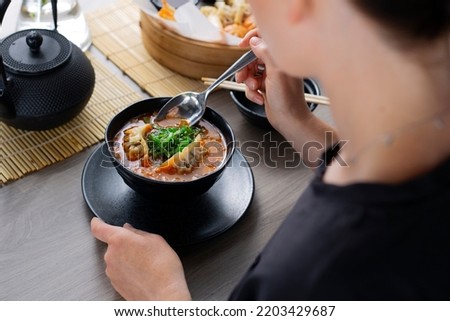 Japanese soup. The woman is eating the soup with chopsticks