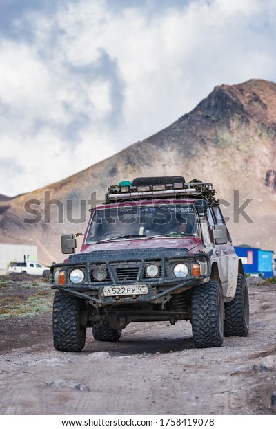 Japanese sport utility vehicle Nissan Patrol driving\
on mountain road on background volcano landscape. Off-road trip in\
volcanic travel destinations. Kamchatka, Russian Far East, Russia -\
Aug 29, 2019