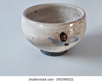 A Japanese Style Bowl With A Crackle Glaze On A White Table Top