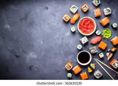 Japanese sushi on a rustic dark background. Sushi rolls, nigiri, maki, pickled ginger, wasabi, soy sauce. Sushi set on a table. Space for text. Top view. Sushi background. Asian or Japanese food frame - Powered by Shutterstock