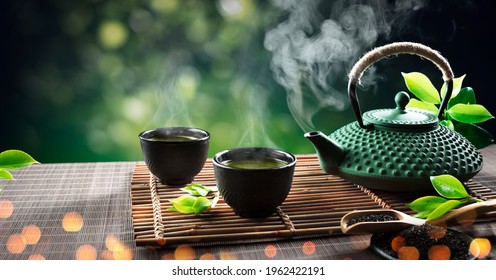 Japanese Tea - Hot Teapot And Teacups On Bamboo Mat