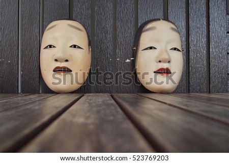 Japanese theater masks made of wooden on brown wood background,male and female mask