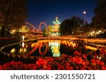 The Japanese Tower and rides at night, reflecting in a lake at Tivoli Gardens, in Copenhagen, Denmark