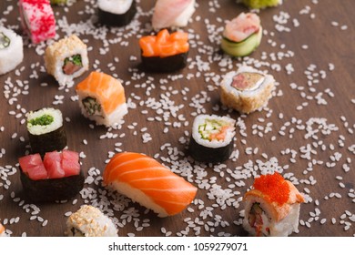 Japanese traditional cuisine. Close up of delicious set of various sushi, rolls and gunkans served on rustic wooden background with spilled rice, copy space