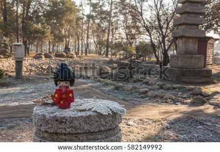 Japanese traditional doll Kokesh against the backdrop of Buddhist stupas and tea house (mass-produced)