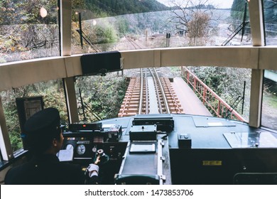 The Japanese train conductor drives the train across the bridge, with beautiful autumn forests on both sides.