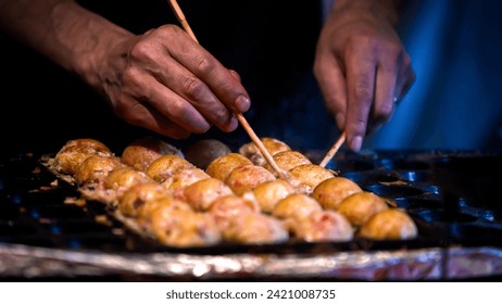 A Japanese vendor prepare a Takoyaki on hot pan food Japan. Process to cooking the popular fried balls with octopus in local street food. Making a Ball-shaped food at asia night market - Powered by Shutterstock