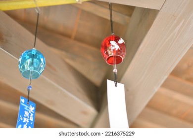 A Japanese Wind Chime Hanging From The Eaves Of A House.