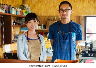 Japanese woman and man wearing blue apron standing in a leather shop, smiling at camera. - Shutterstock ID 1825181063