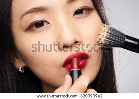    Japanese woman paints lips applying makeup brush                            
