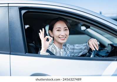 Japanese woman in plain clothes driving a car - Powered by Shutterstock