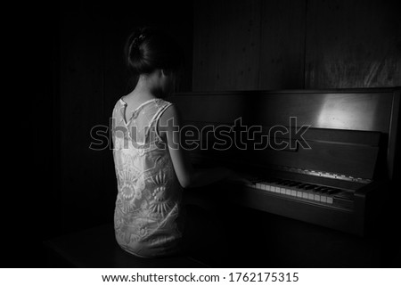 
Japanese woman playing the piano in a dim room