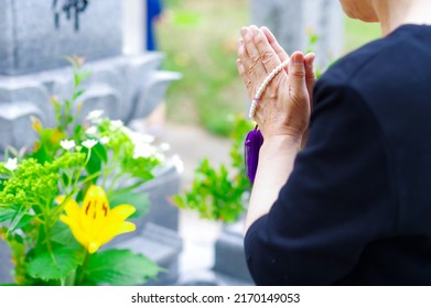 A Japanese woman putting her hands together at the grave, the style of visiting a Japanese grave - Shutterstock ID 2170149053