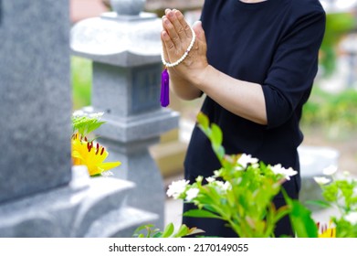 A Japanese woman putting her hands together at the grave, the style of visiting a Japanese grave - Shutterstock ID 2170149055