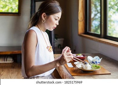 Japanese woman sitting at a table in a Japanese restaurant, eating. - Shutterstock ID 1825175969