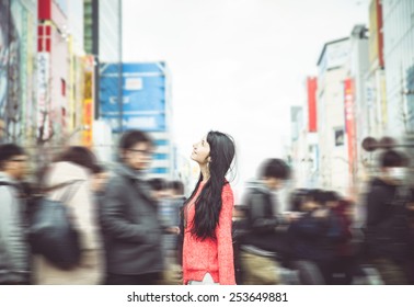 Japanese Woman Standing In The Crowd In Tokyo City Center. She Looks Amazed At The Buildings