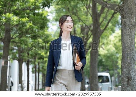 A Japanese woman in a suit standing in the fresh green