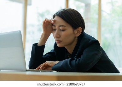 Japanese woman tired of work - Shutterstock ID 2180698737