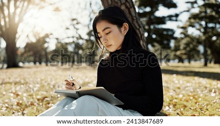 Japanese woman, writing and book in park, thinking and relax by tree, grass or sunshine for peace. Girl, person or student with story in nature, college or notes with vision, knowledge or campus lawn