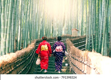 Japanese women are in Kimono and walking through Arashiyama Bamboo forest in Kyoto, Japan.