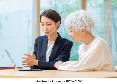 Japanese Women And Senior Women In Suits Looking At A Computer