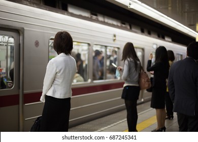 Japanese Women Waiting For Their Train On A Subway Platform In Tokyo.