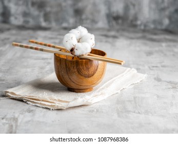 Japanese Wooden sticks and wooden bowls with cotton flower on gray stone background. Wabi Sabi style. Horizontal. Copy space. Minimalism.