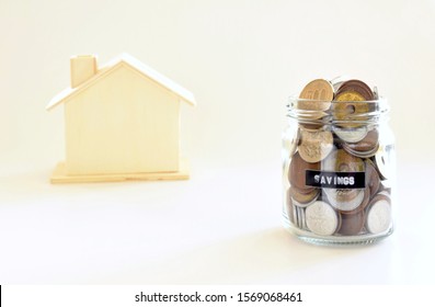 Japanese Yen coins collected in savings glass jar with blurred wooden house model on white background. Concept for financial home loan or money savings plan for house buying - Shutterstock ID 1569068461