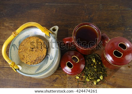 Japan's teapot and cups with green tea on wooden plank on dark wooden background