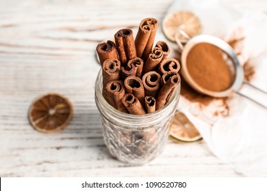 Jar With Aromatic Cinnamon Sticks On Wooden Background